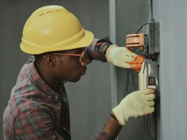 Electrician in a hard hat working on an electrical panel